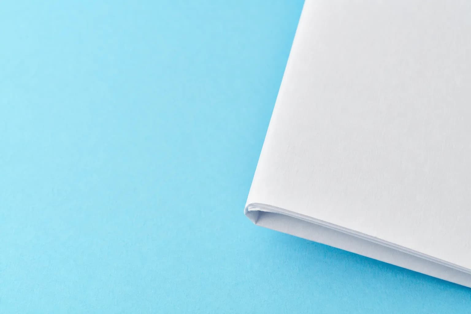 Tight close-up of a folded blank household bill on a white countertop, positioned on the right with open space beside it.